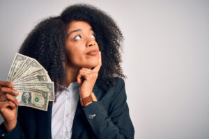 Young woman holding money with a pondering look